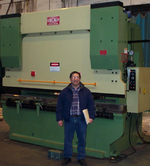 Photo of Larry standing in front of a Chicago D & K 240 ton Brake Press machine.